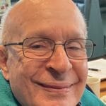 An elderly man with glasses smiling at the camera for NarfOfficers.